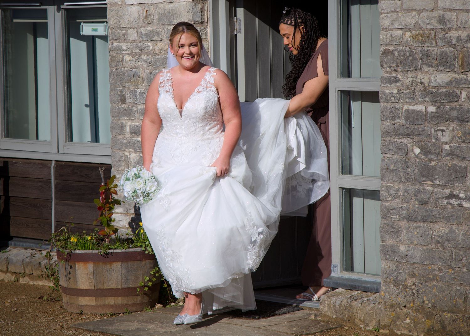 A person in a white wedding dress sits on stone steps with sunlight casting shadows.