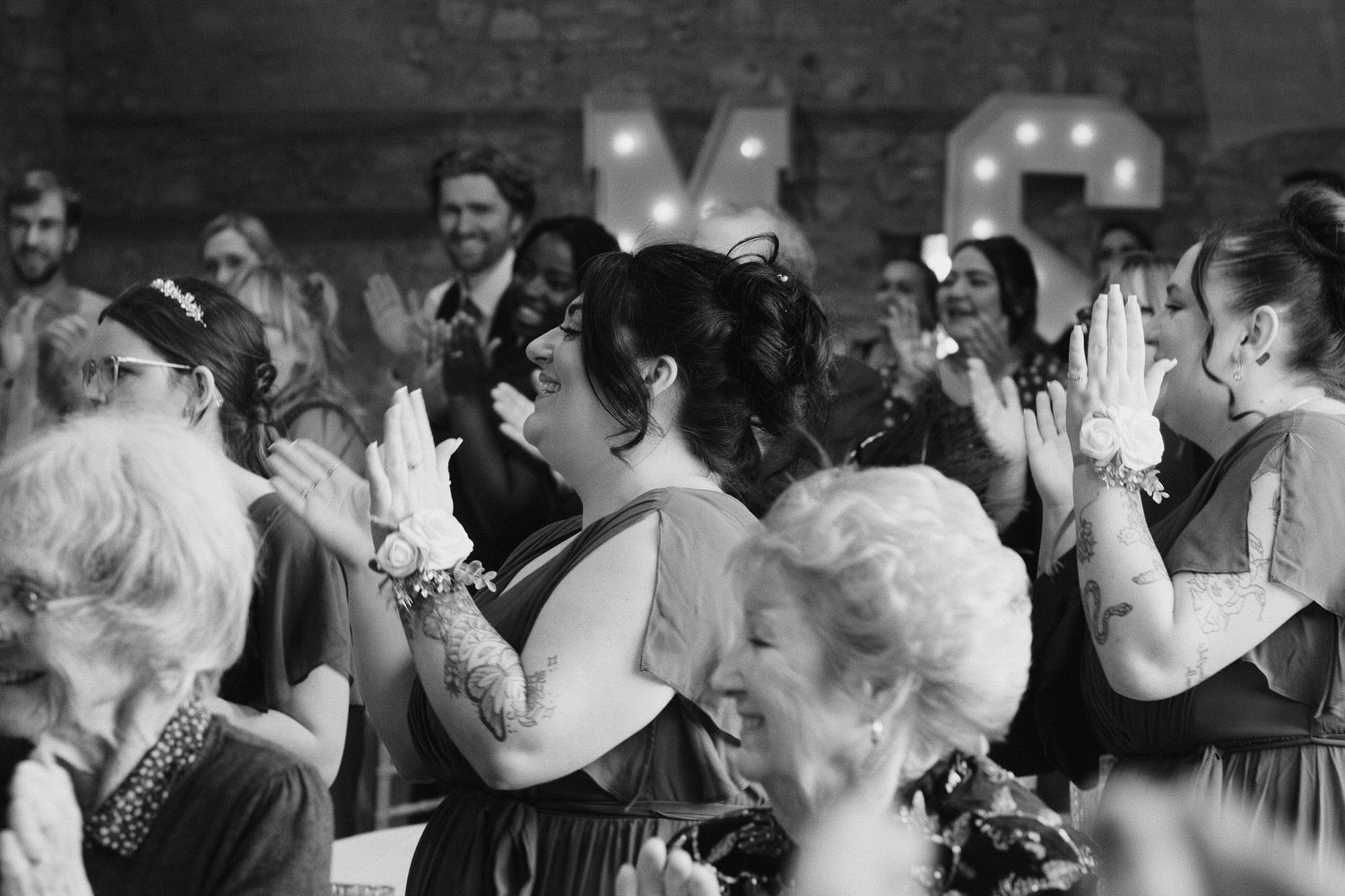 Black and white photo of wedding guests dancing and celebrating on dance floor.