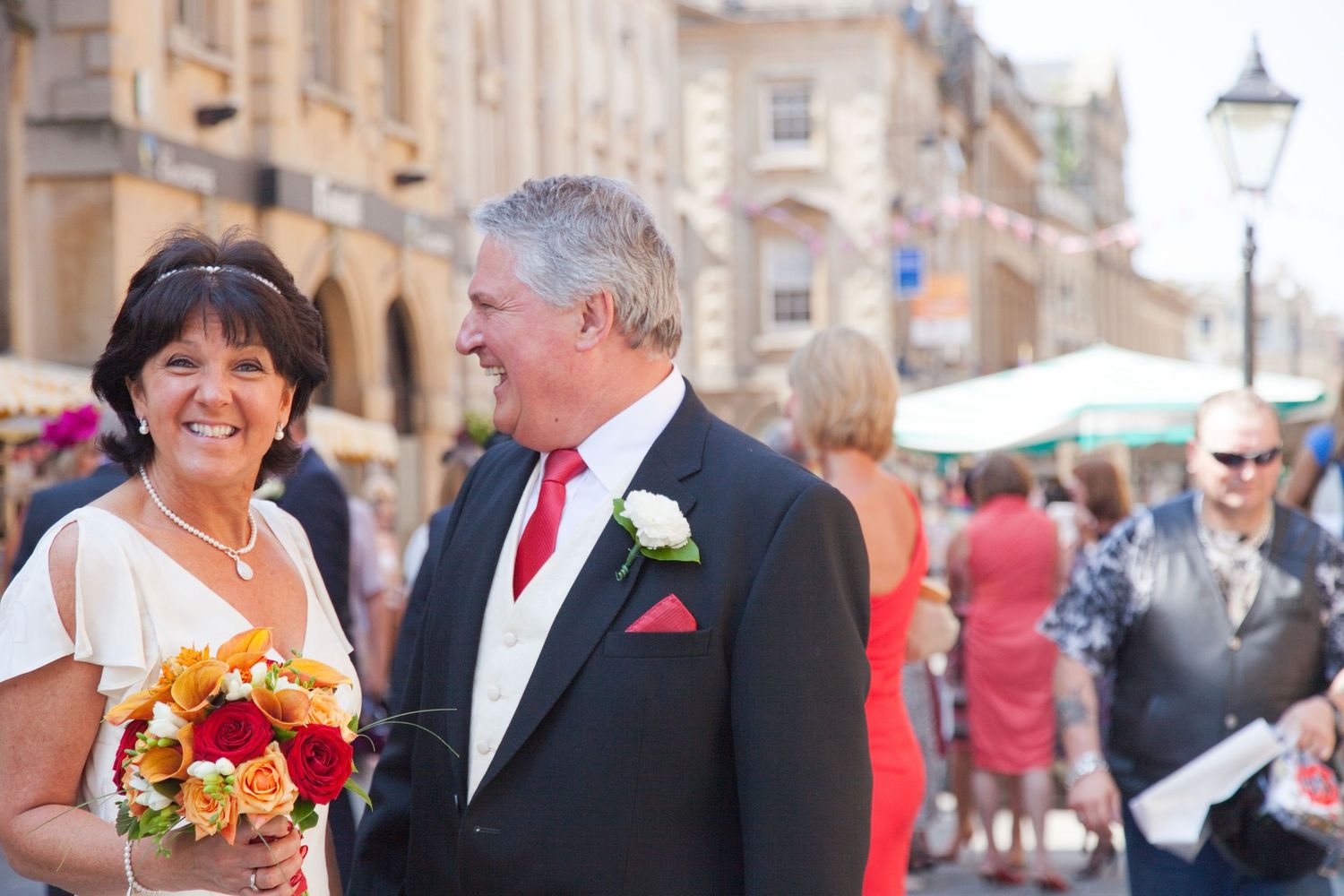 A happy couple poses together during their wedding celebration on a historic street.