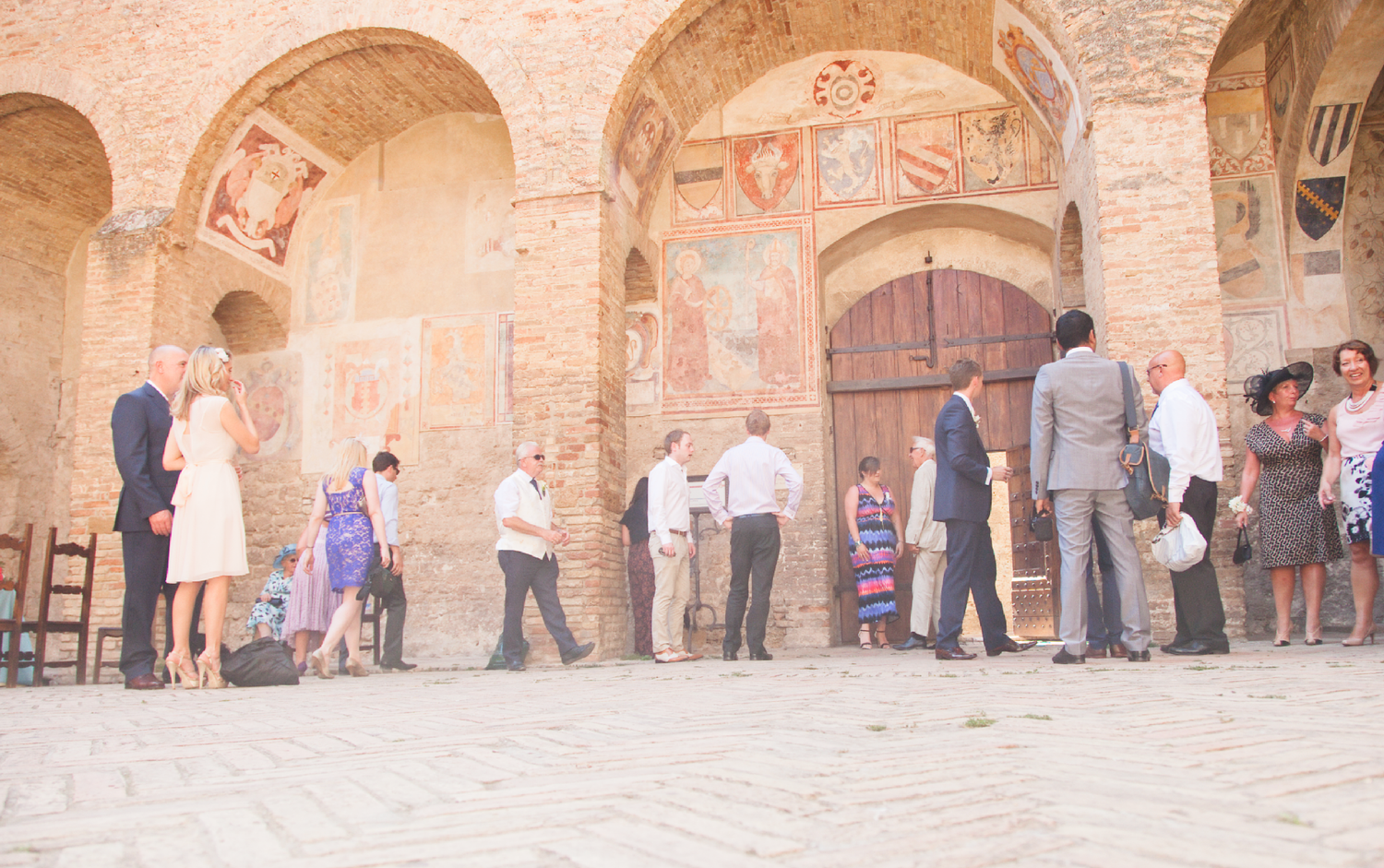 People line up under ornate arches with frescoes at a historic venue.