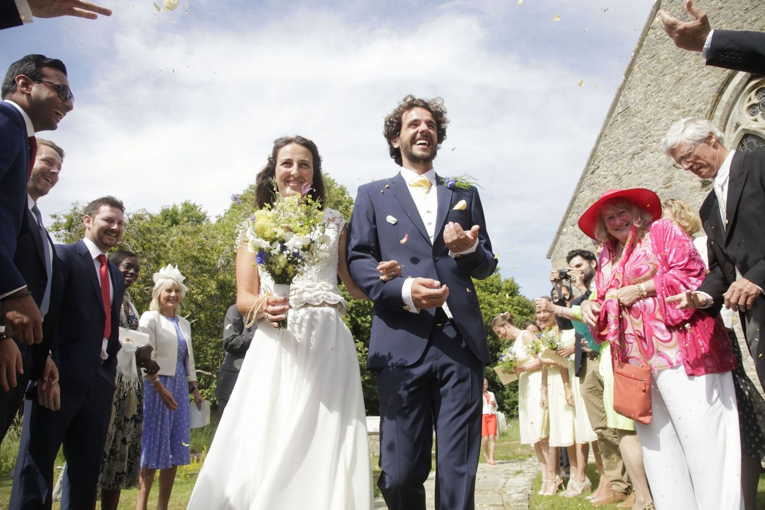 Wedding party and guests gather outside for a celebratory confetti moment.