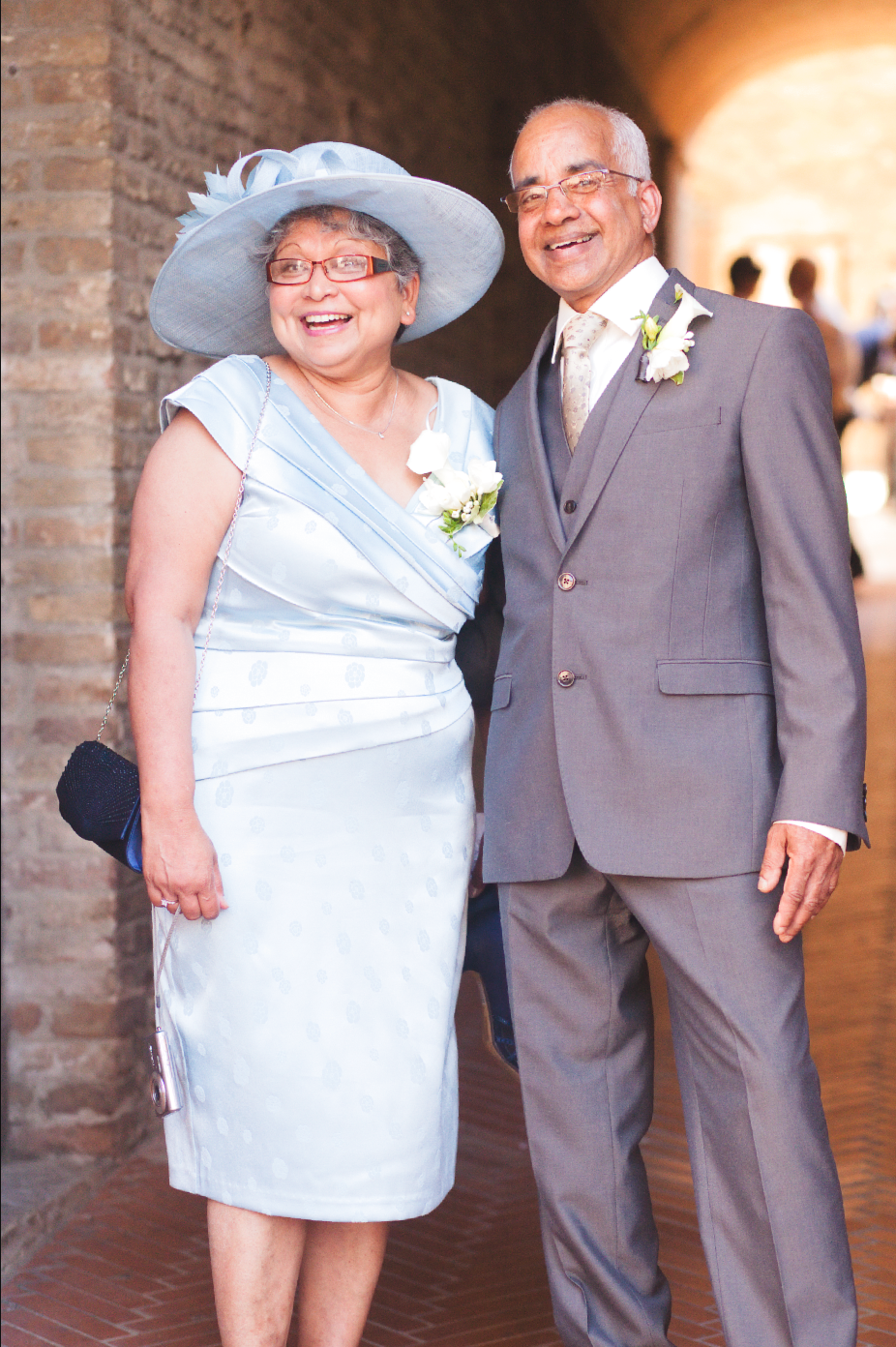 Wedding attendees pose for formal portraits in an elegant brick corridor.