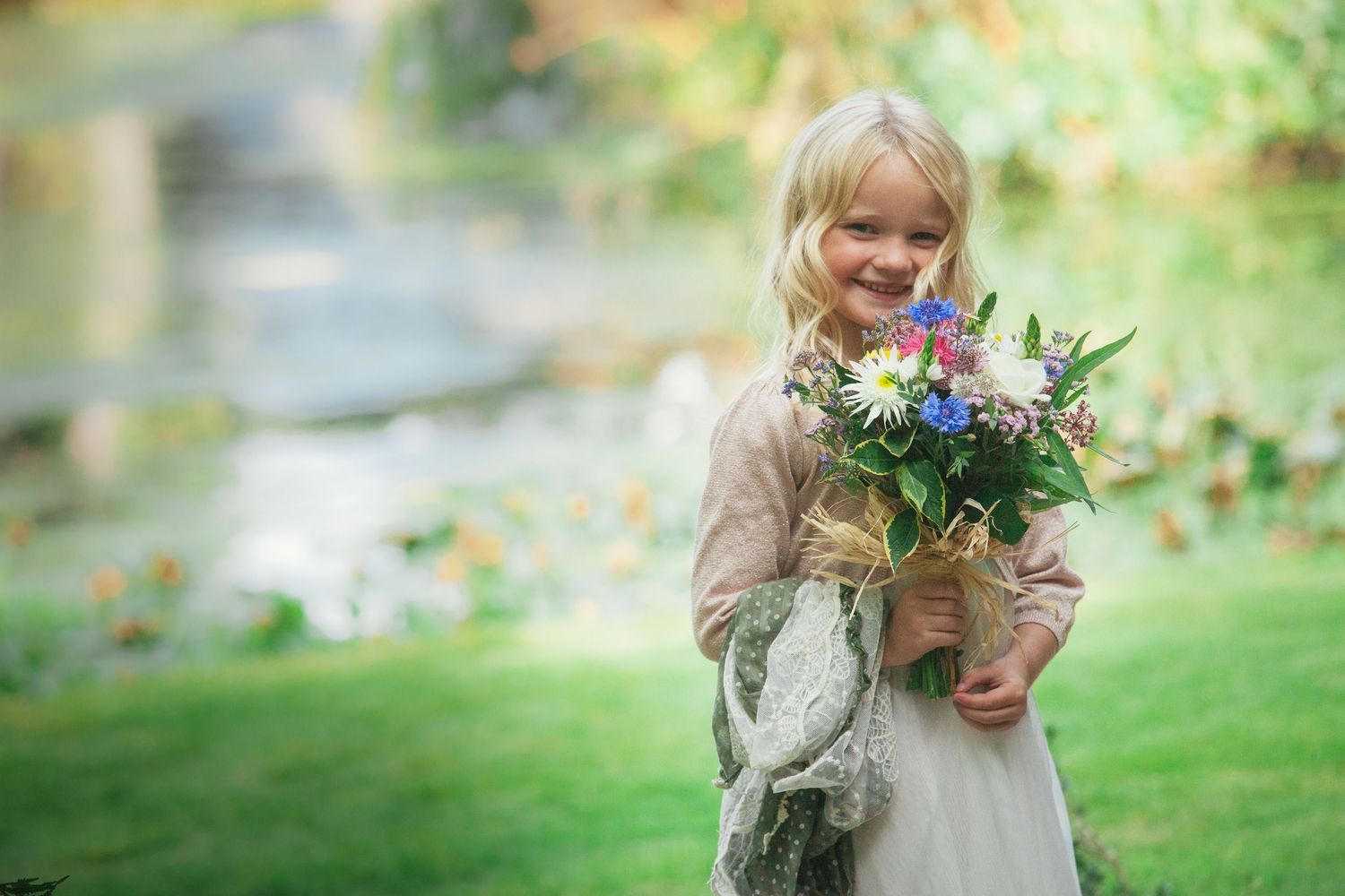 Bridemaid at the water's edge smiling with a boquet at a wedding in Somerset.