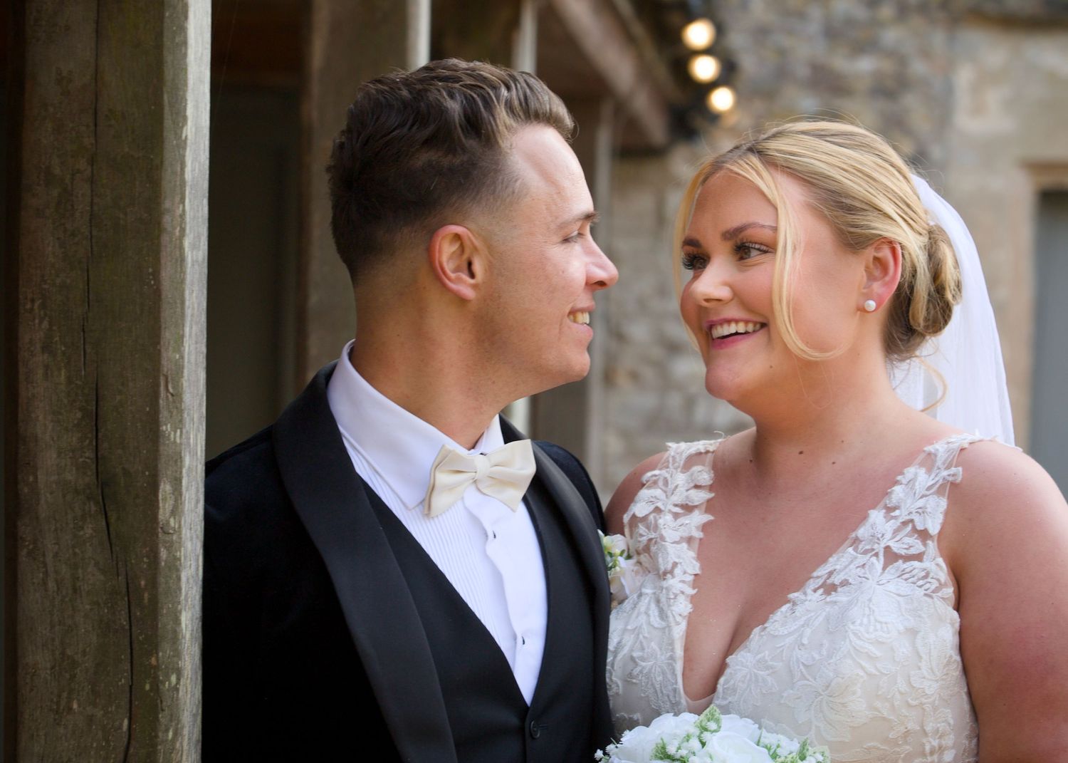 Intimate wedding portraits captured against textured stone wall background.