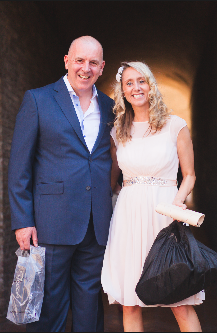 Formal wedding portraits taken in a dimly lit stone passageway.