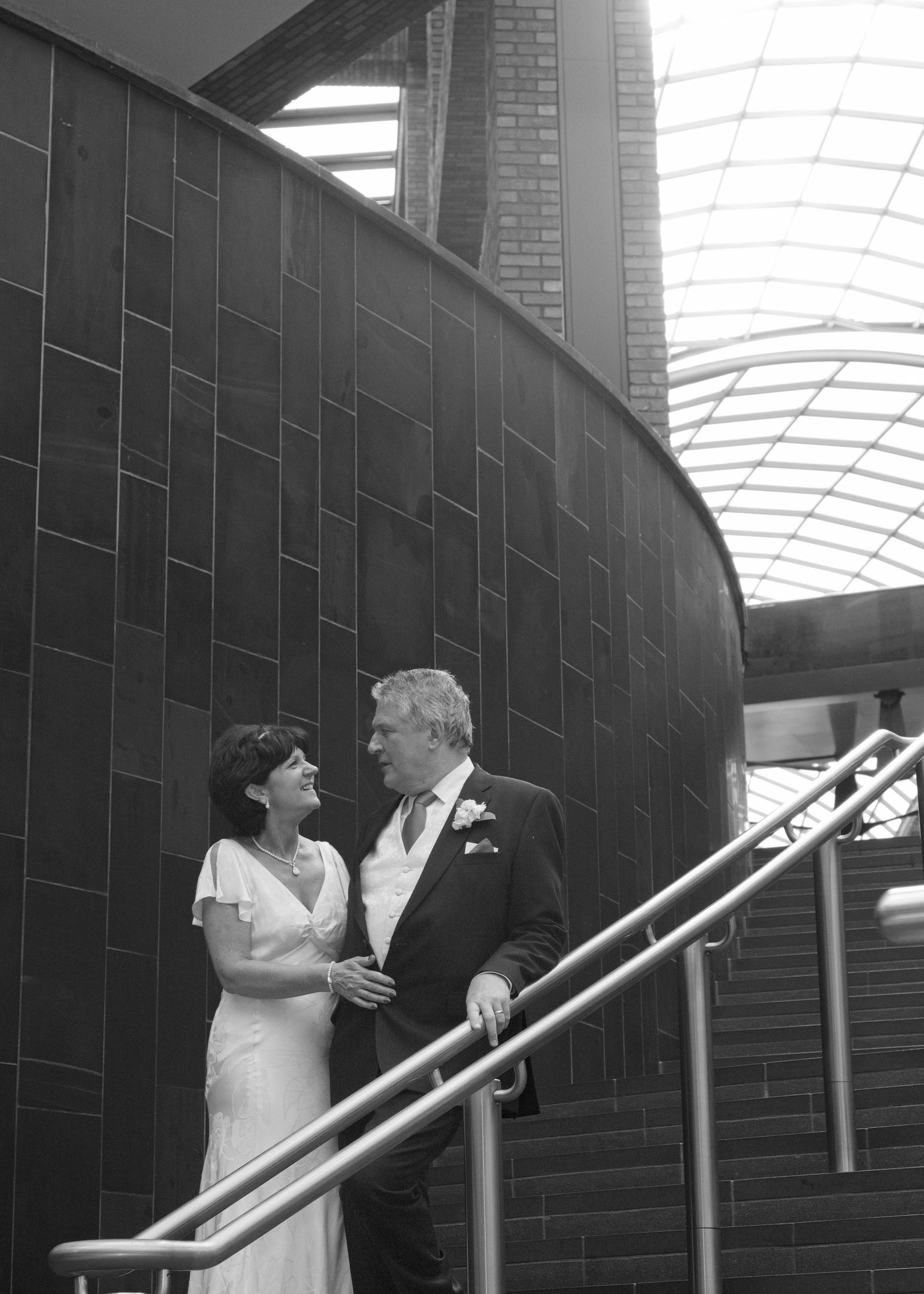 A romantic wedding couple shares a sweet moment on an industrial staircase with brick walls.