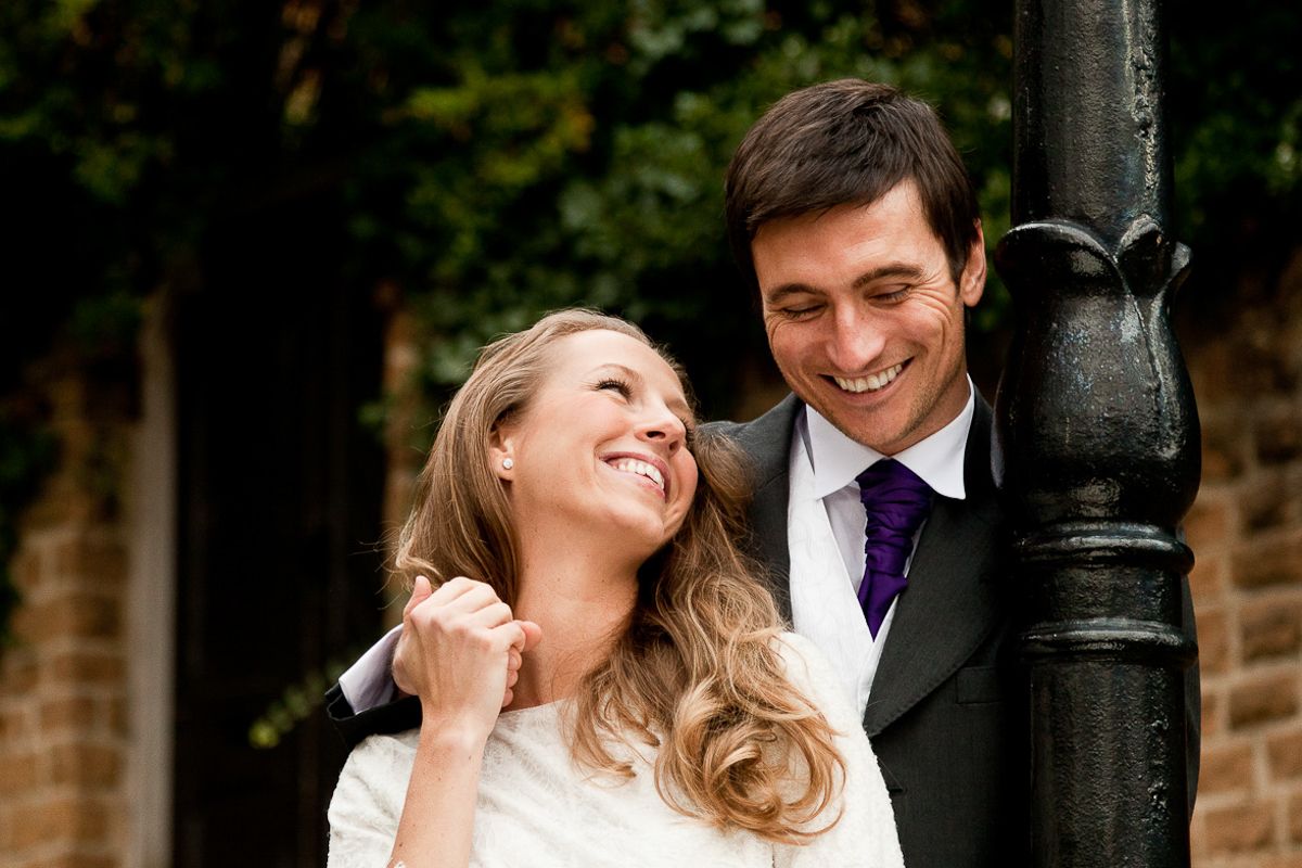 Couple sharing romantic moments against brick wall and lamp post.