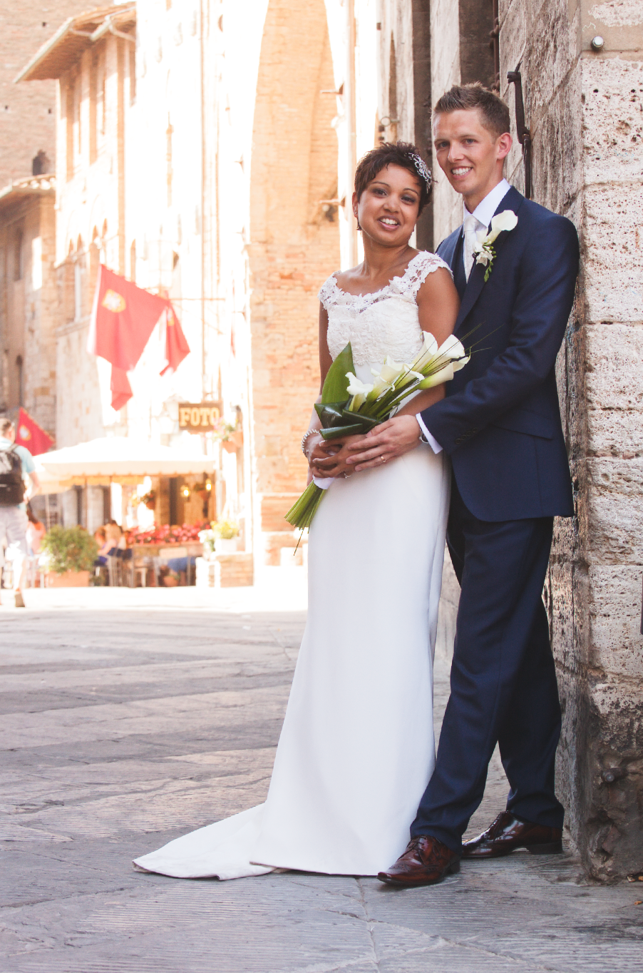 Romantic wedding portrait against stone architecture with natural lighting.