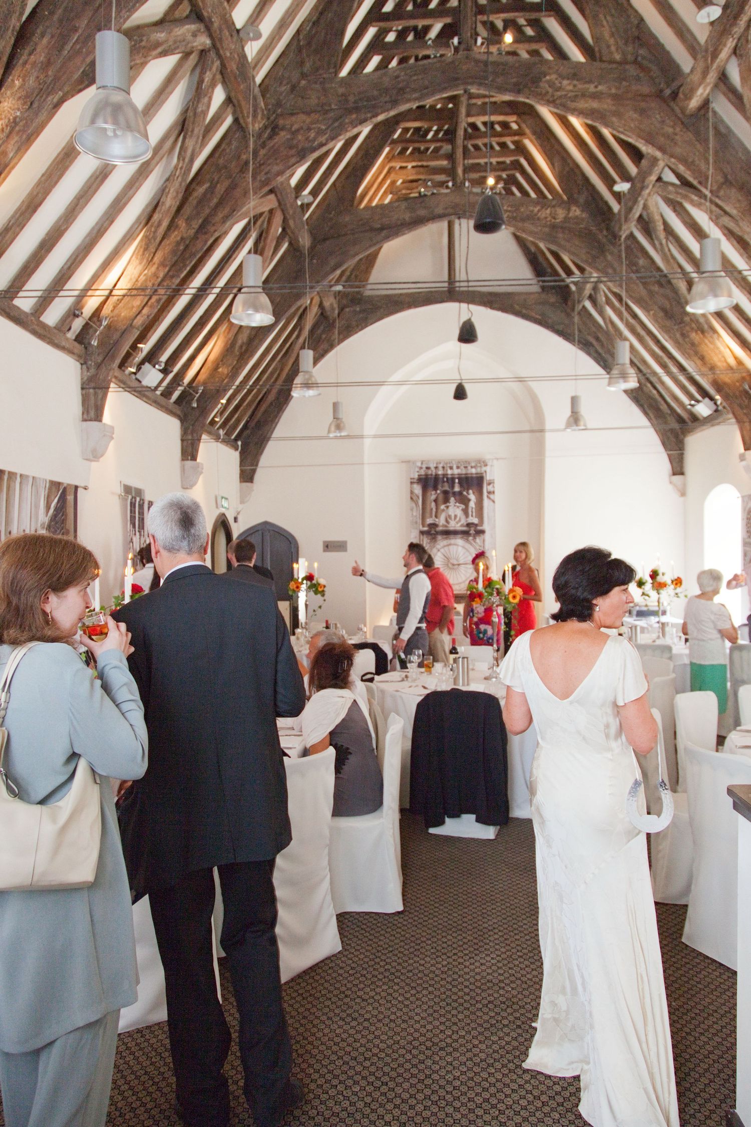 Wedding reception in a rustic venue with exposed wooden beams and white decor.