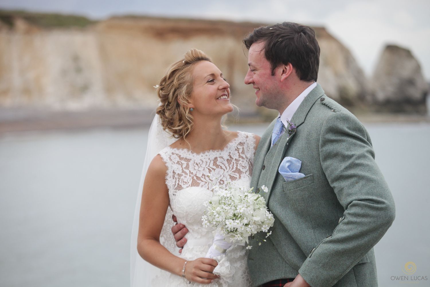 Newlyweds share a romantic moment near ocean cliffs on their wedding day.