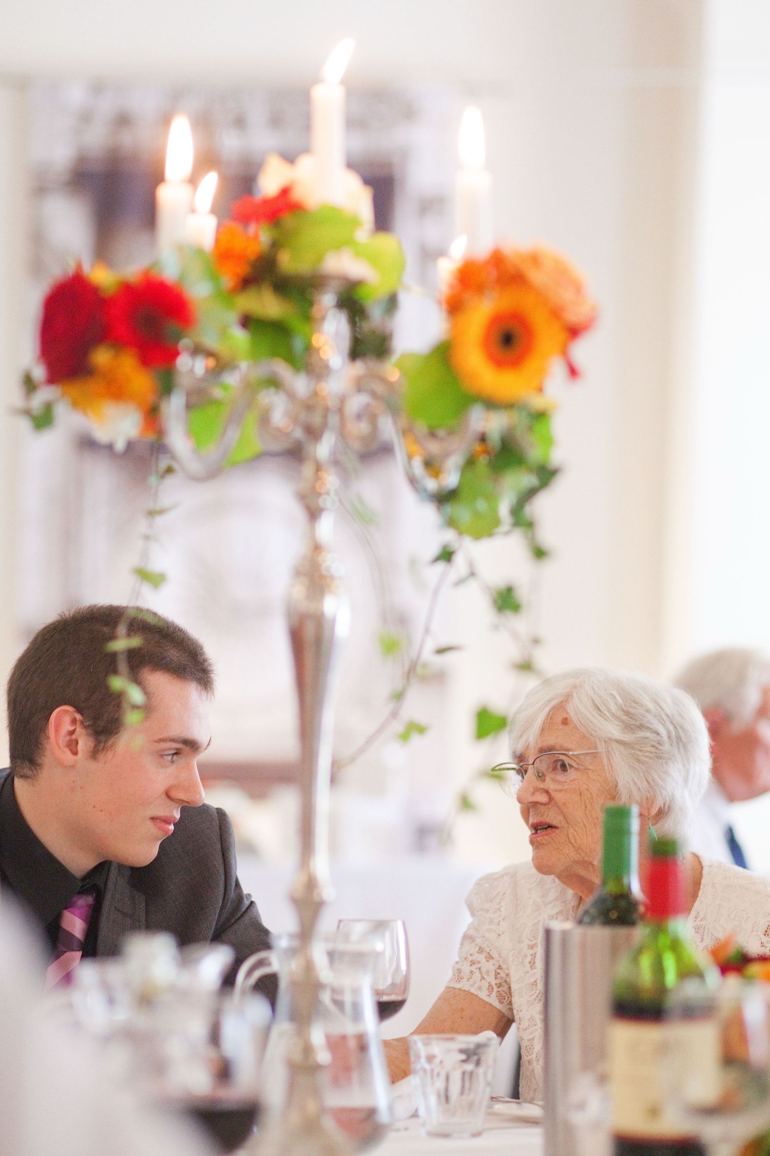 Wedding reception guests engaged in conversation at tables with bright floral centerpieces.