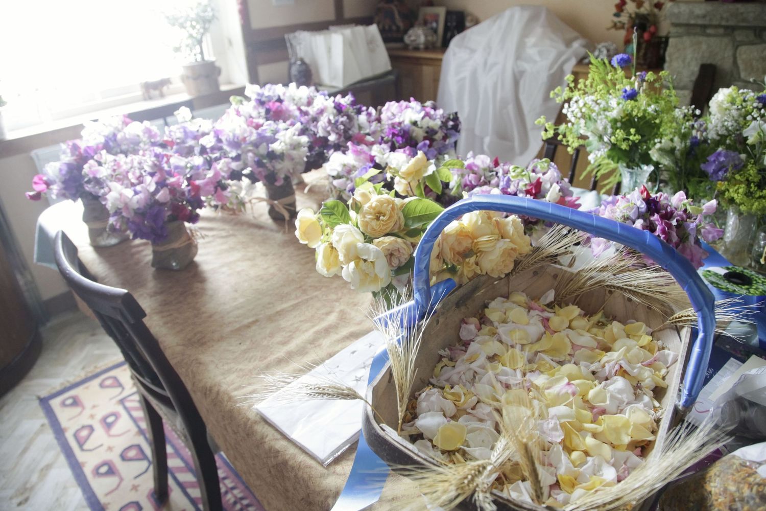 Multiple trays of colorful flower arrangements spread across a rustic wooden table.