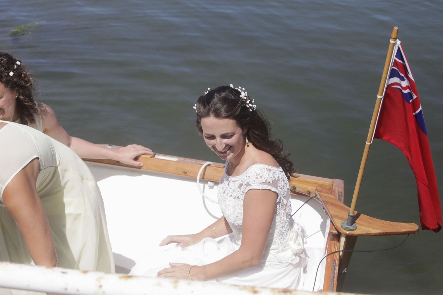 A decorated wooden boat with a red flag displays white fabric and floral arrangements on the water.