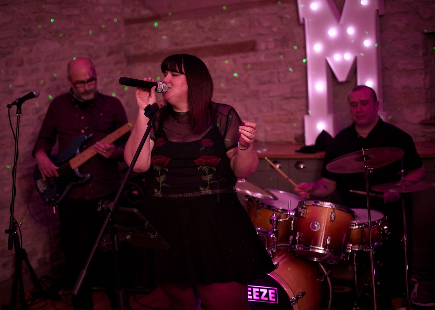 Band performing on stage with pink neon lighting and live instruments.