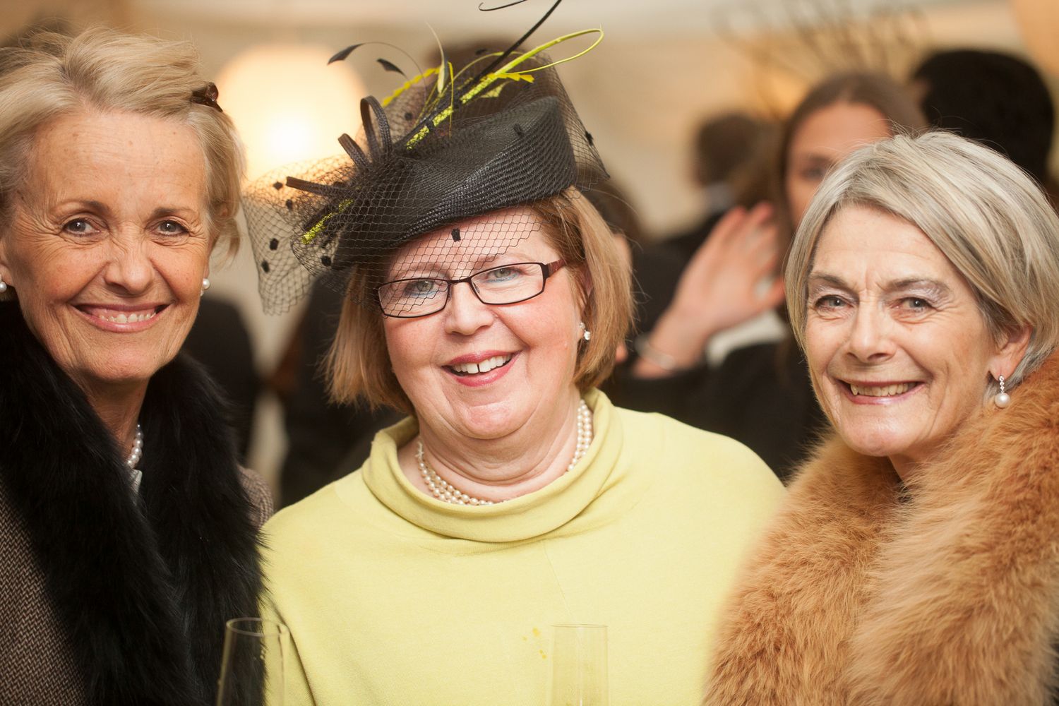 Group of wedding guests smiling in formal attire at reception.