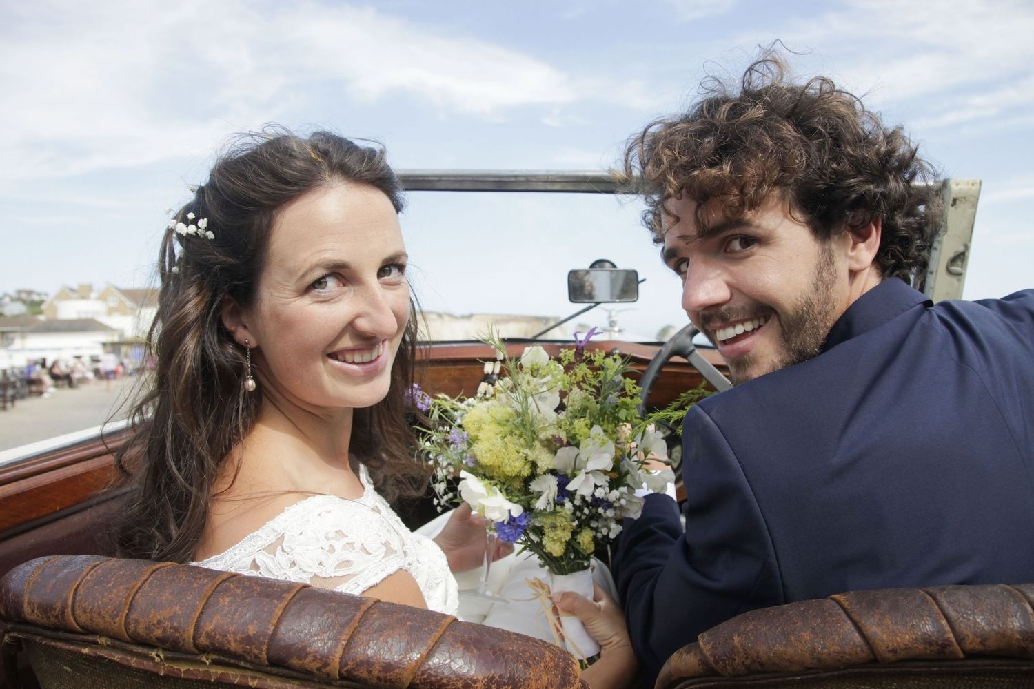 Bride and groom in their convertible vintage wedding car during their beach wedding bridal photo shoot.