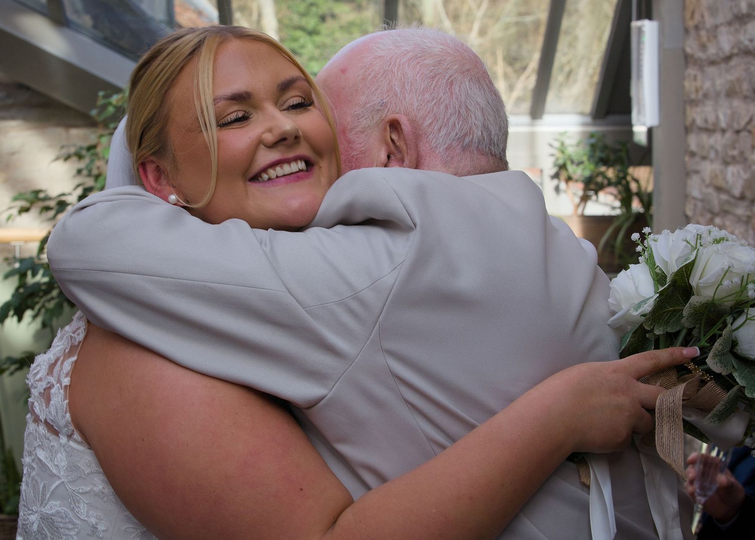 An emotional embrace captured during a wedding celebration with white floral decorations.