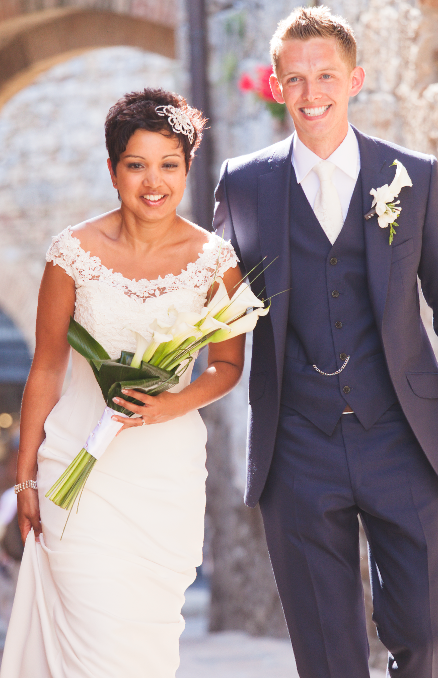 Elegant wedding couple walking together holding white calla lily bouquet.