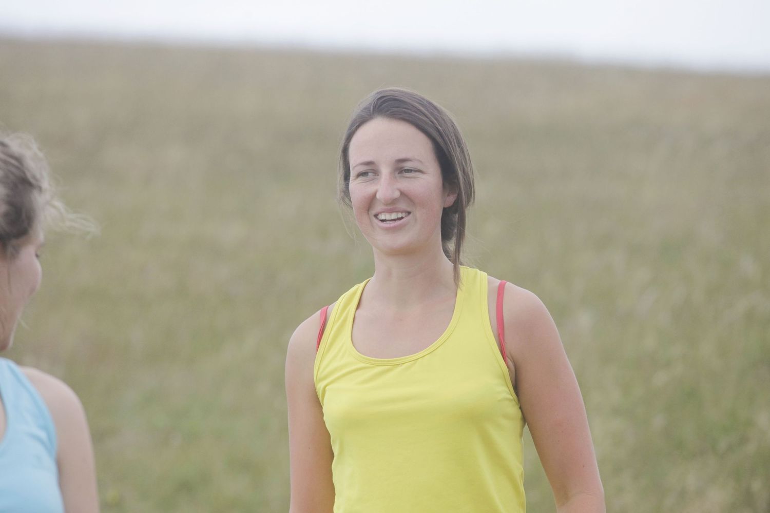 People in athletic wear enjoying sunny day on grassy coastal path.