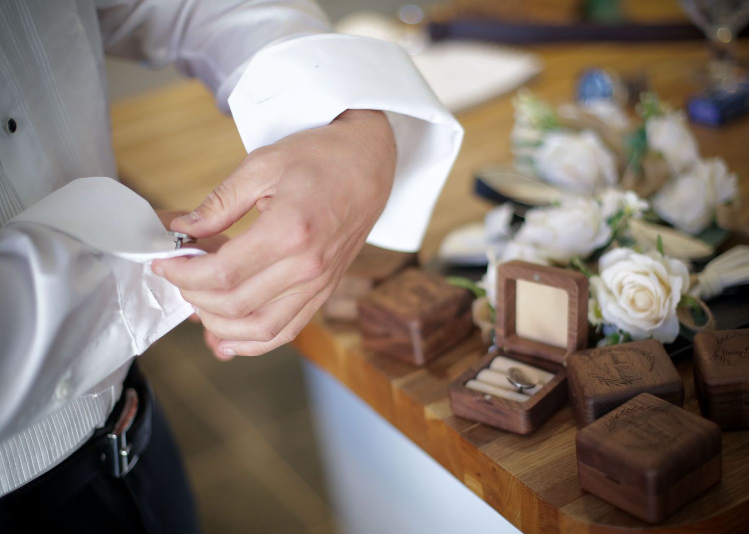 Close-up of hands arranging small brown gift boxes with white ribbons.