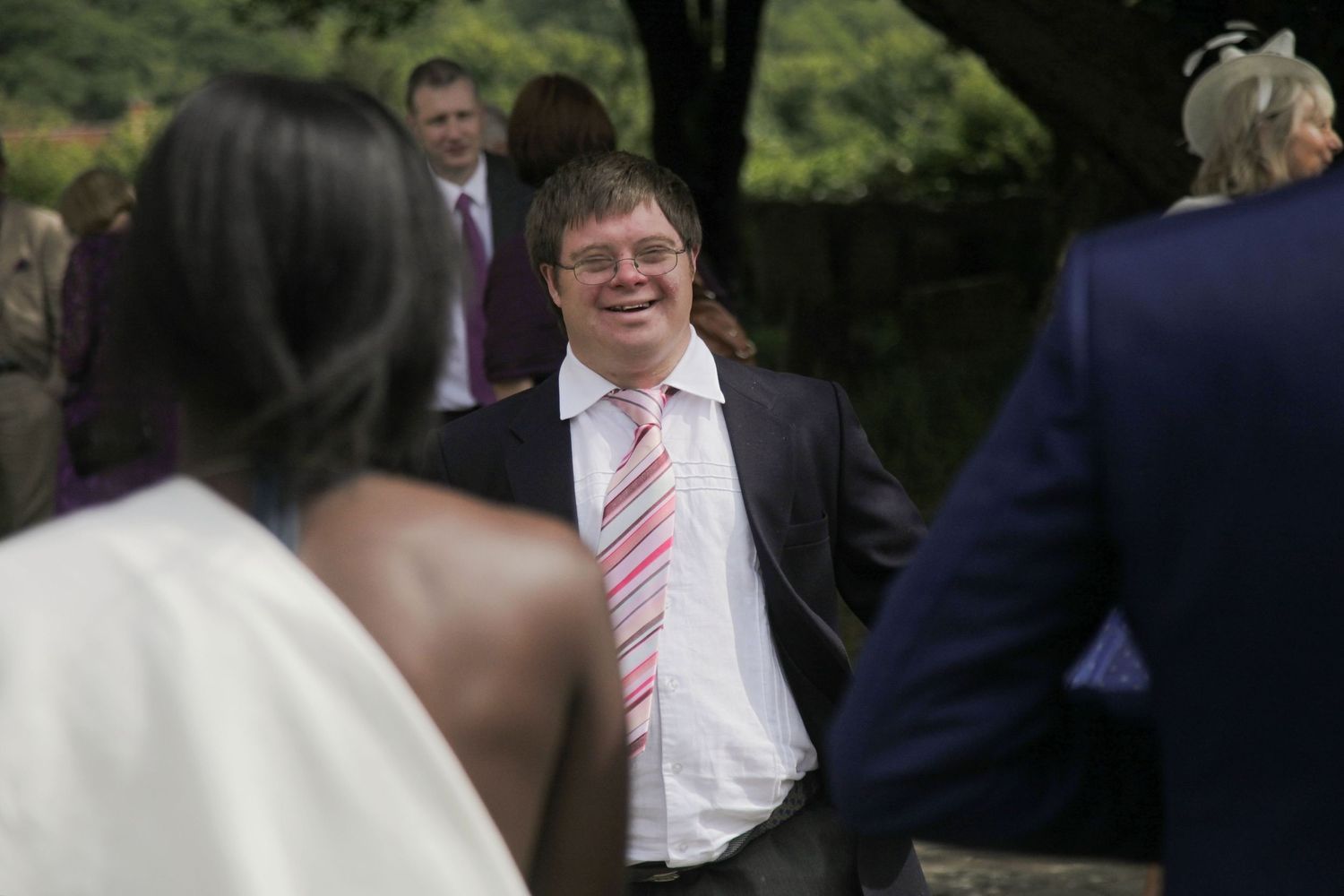 Wedding guests and party members gather outdoors during a summer celebration.