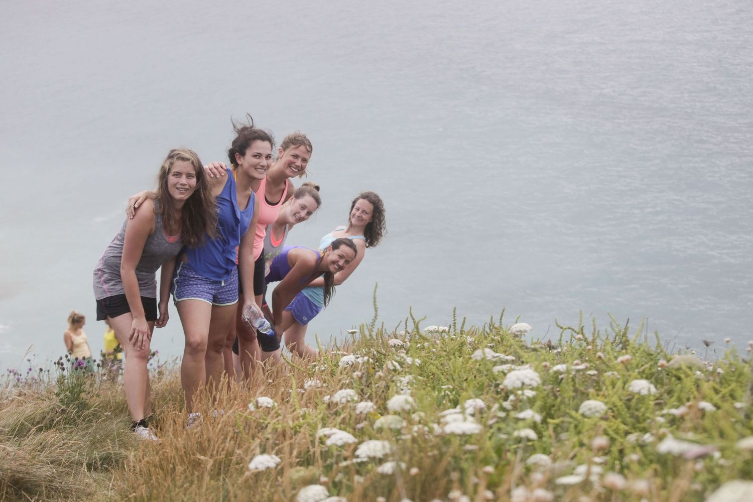 Group enjoying wildflowers on clifftop meadow overlooking ocean views.