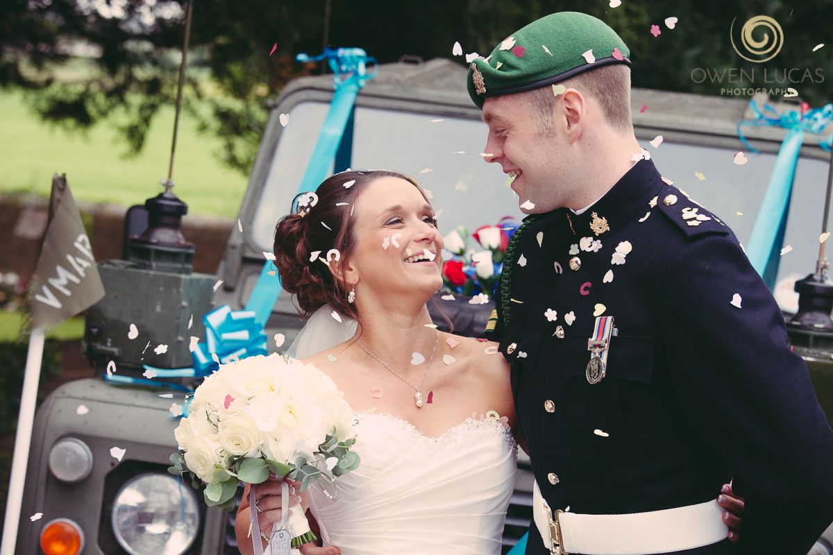 Military wedding couple shares joyful moment with confetti falling around them.