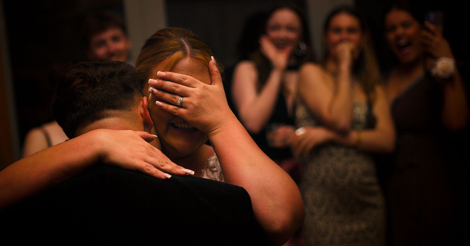 Emotional moment captured during a wedding reception with guests in the background.