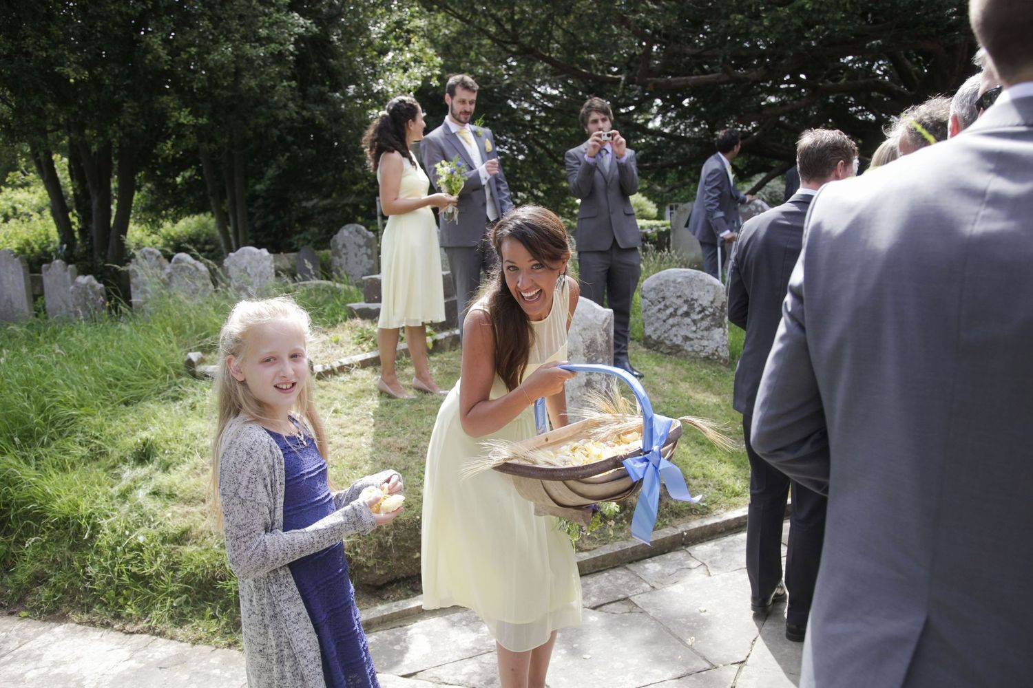 Wedding guests mingle in a sunny outdoor church setting.