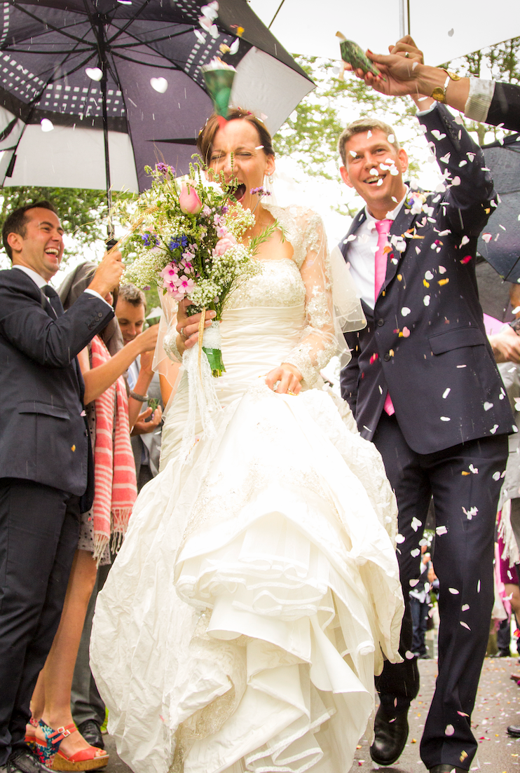 Confetti fills the air as wedding guests celebrate around the bride in her flowing white dress.