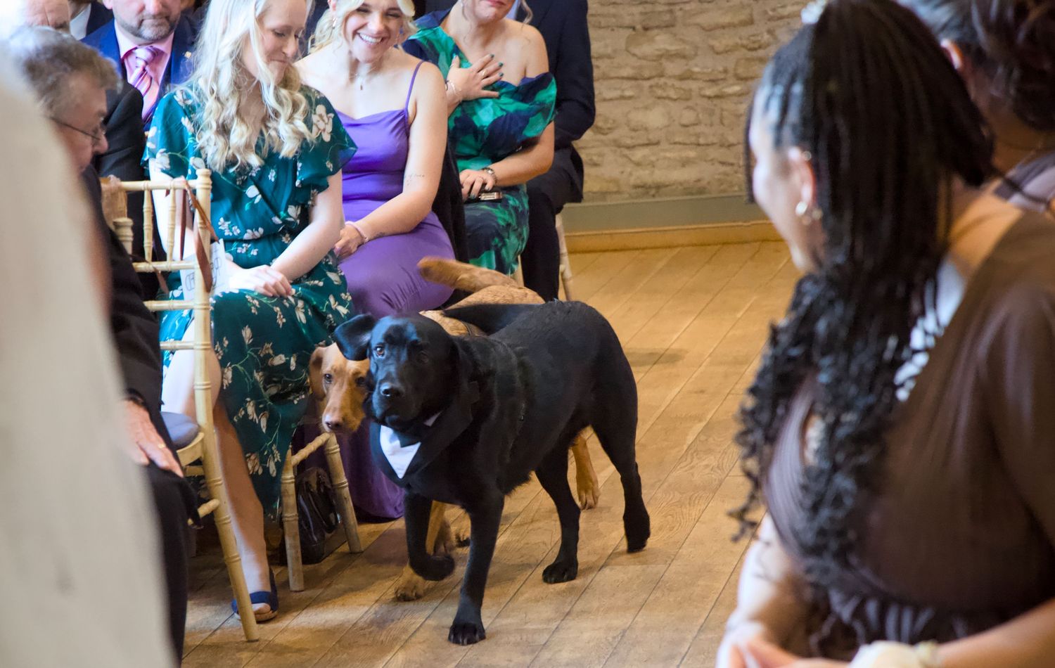 Wedding guests dancing and celebrating on a wooden dance floor at a reception.
