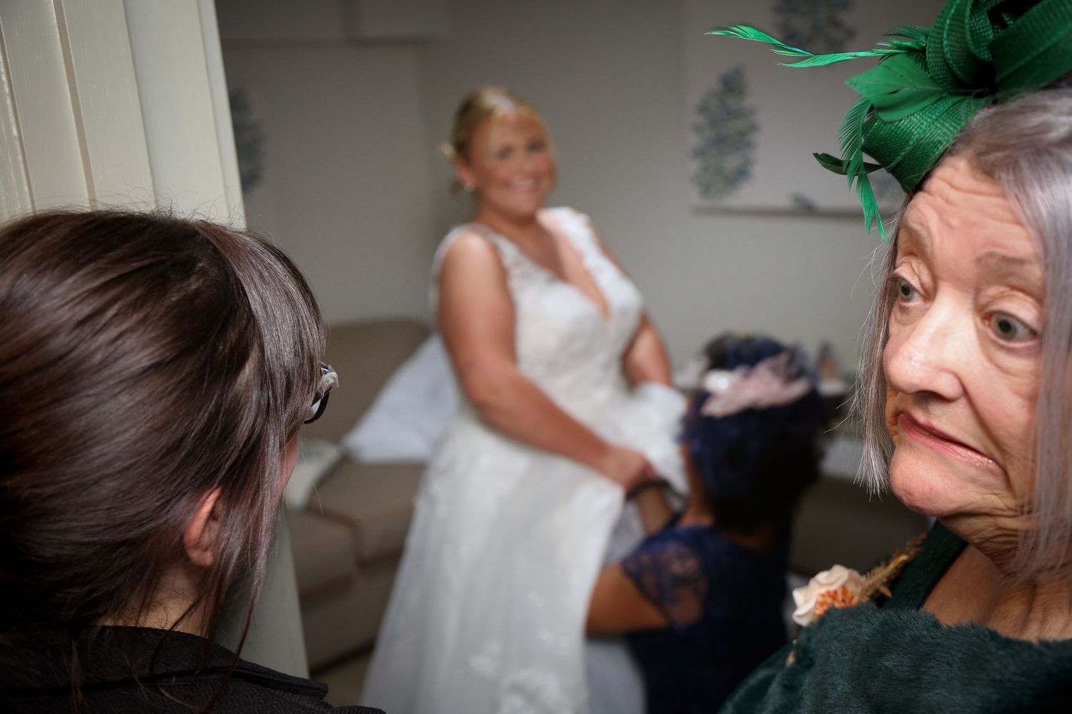 Wedding preparation scene with multiple people, featuring a bride in a white dress.