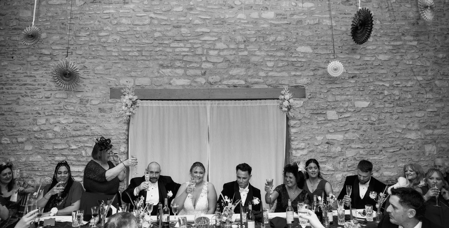 Long banquet tables set for wedding reception in rustic brick-walled venue.