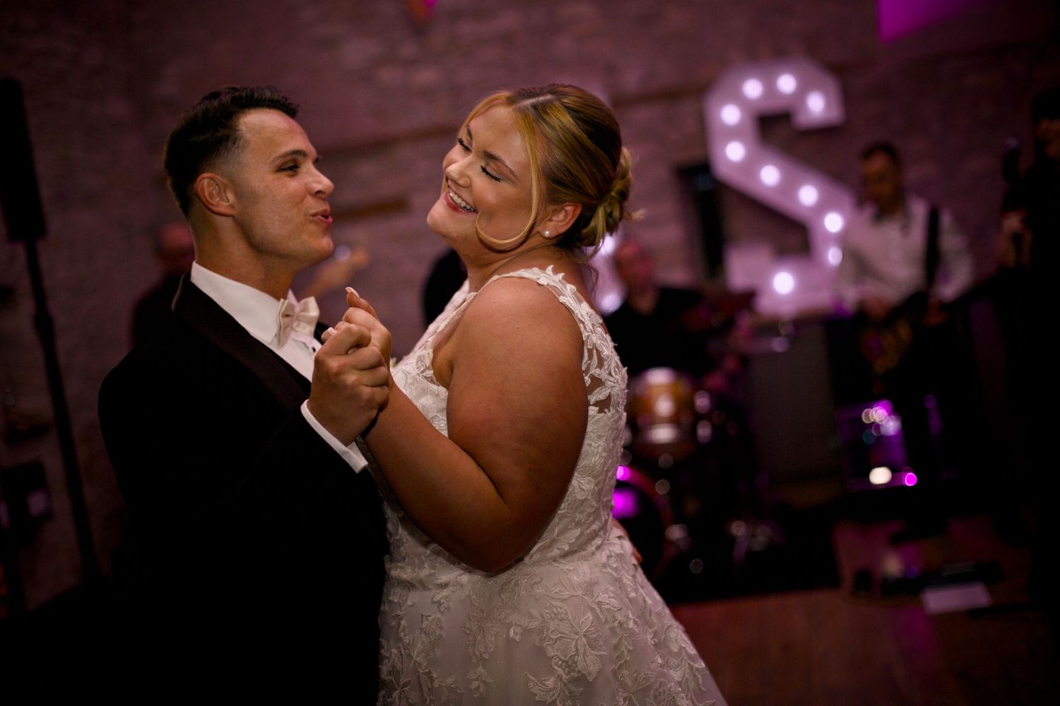 Couple dancing in an intimate moment under purple ambient lighting at their wedding reception.