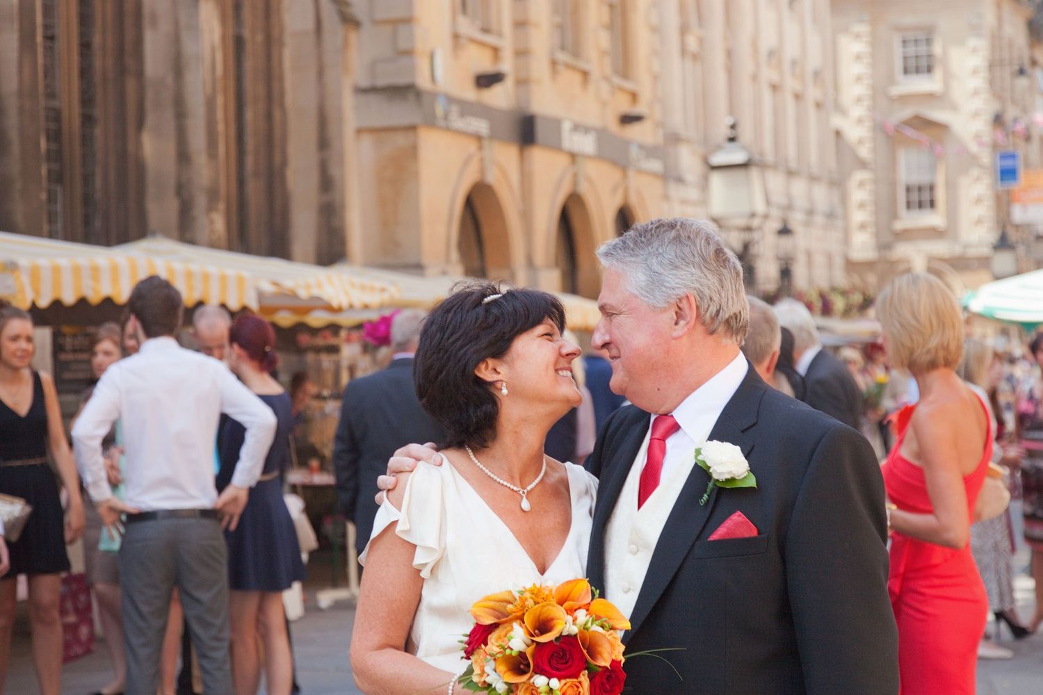 A couple shares an intimate moment during their wedding celebration on a historic street.