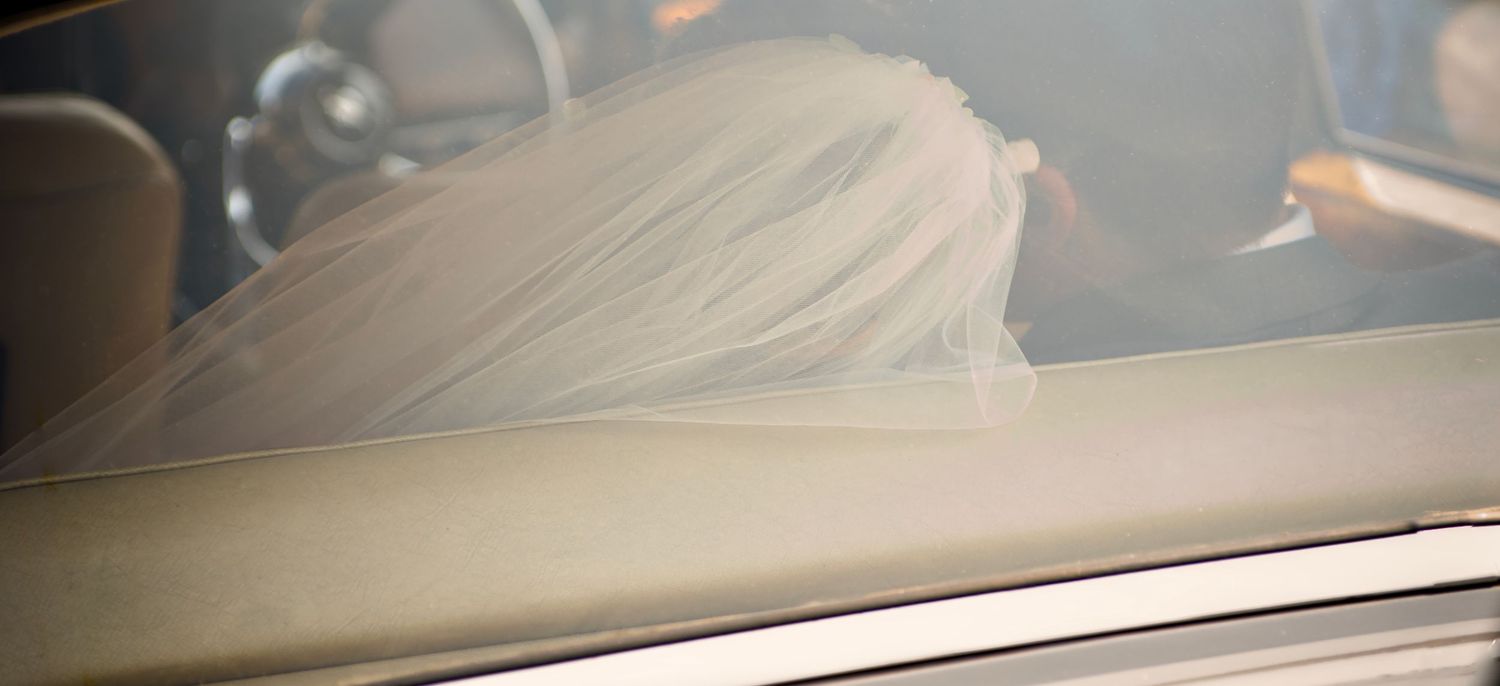Bride cuddles her groom in their wedding car after the wedding ceremony.