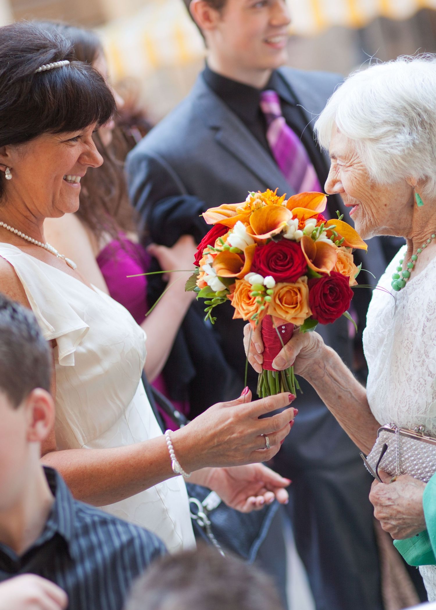 Colorful bouquets of orange and red roses add vibrant touches to a wedding celebration.