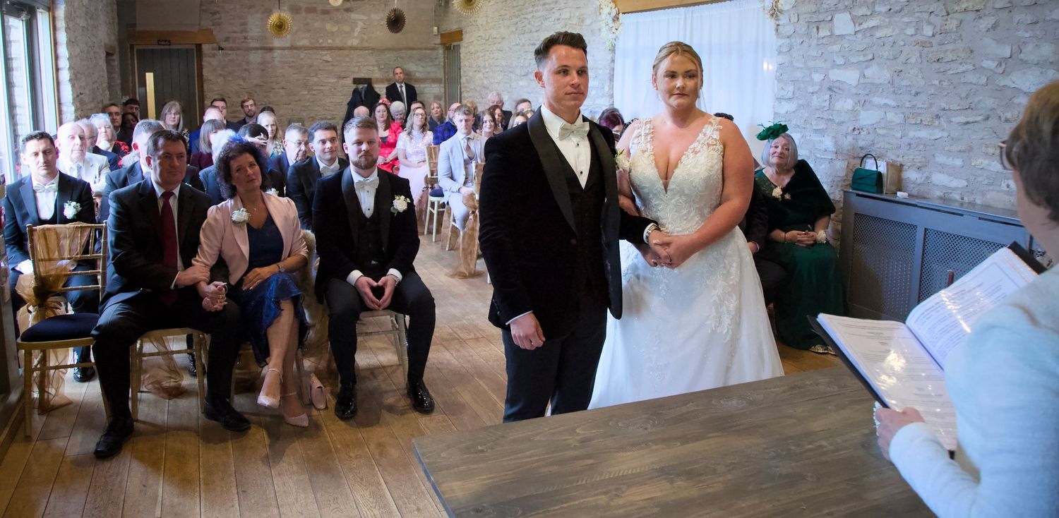 Wide view of a wedding reception in a rustic venue with stone walls and natural lighting.