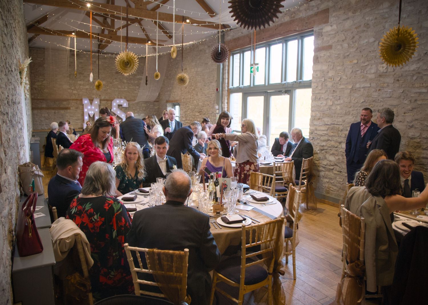 Wedding reception venue with exposed brick walls and elegant table settings in rustic barn setting.