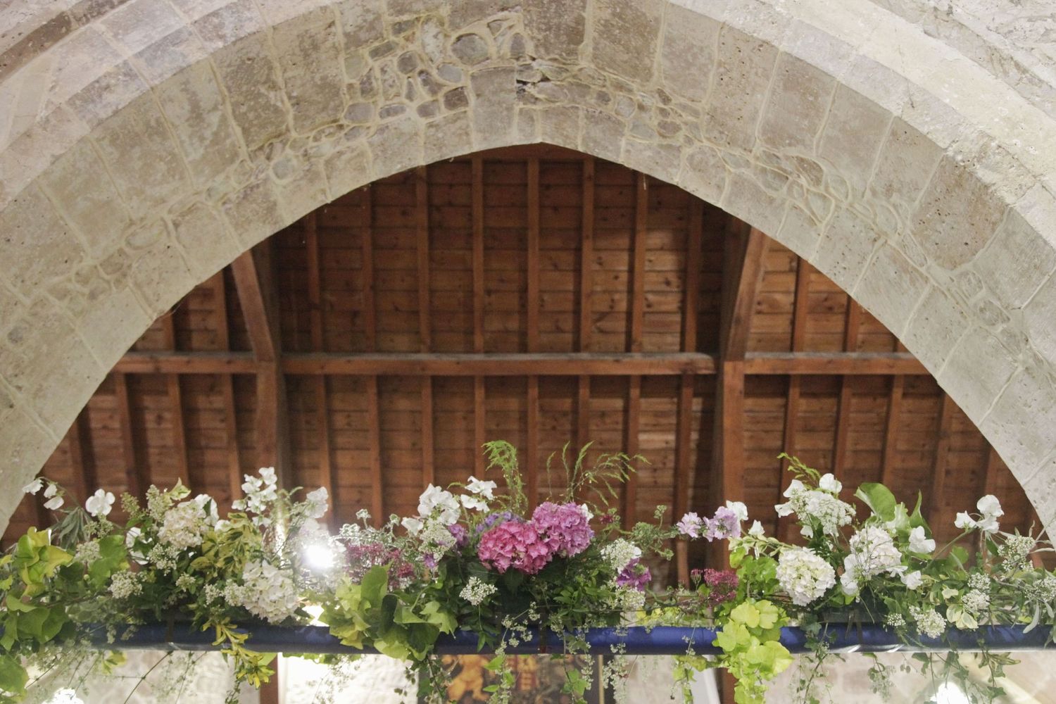 Wedding party members in dark suits with yellow accents stand together under stone archways.