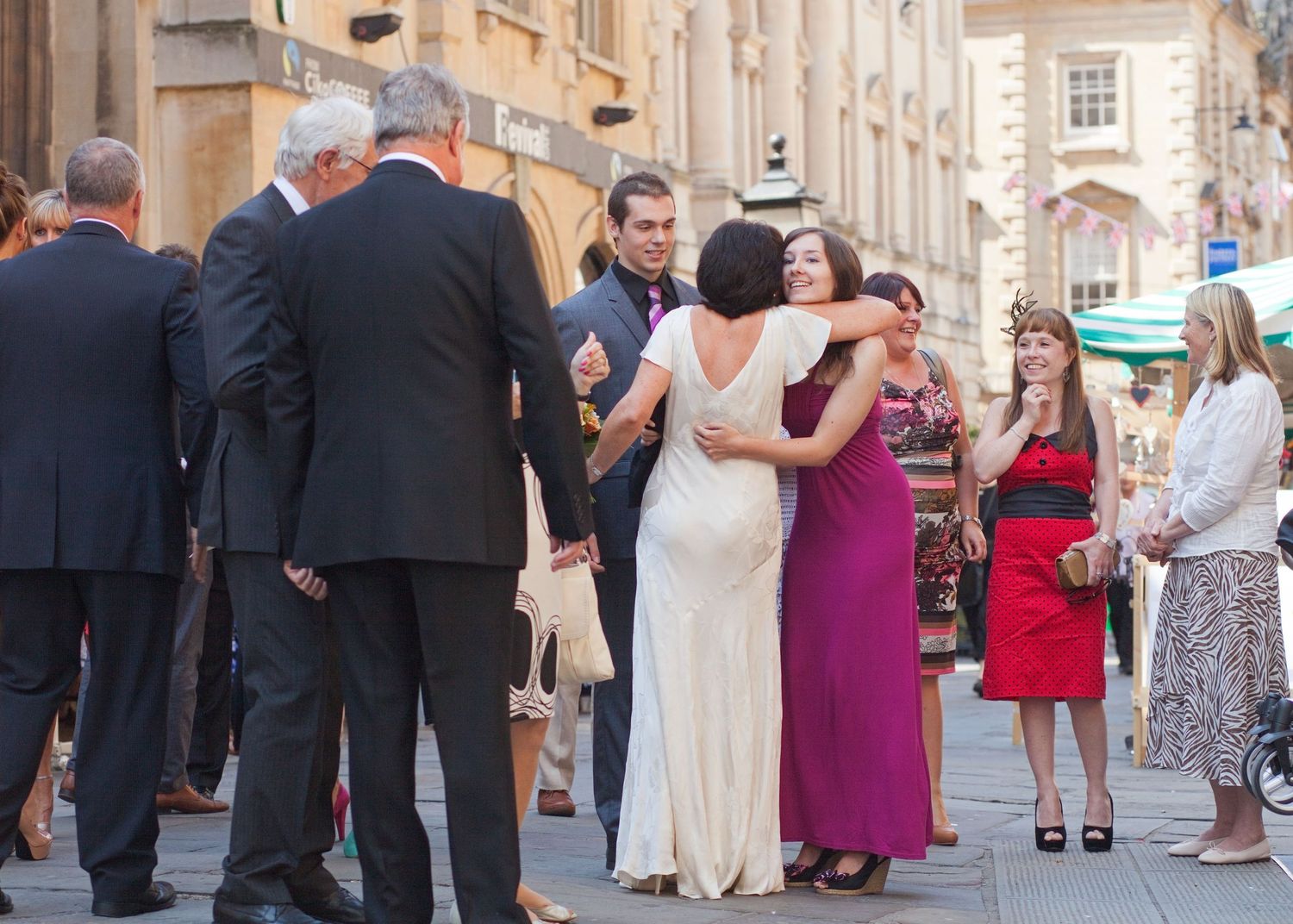 Wedding guests gather outside a stone building for a celebration.