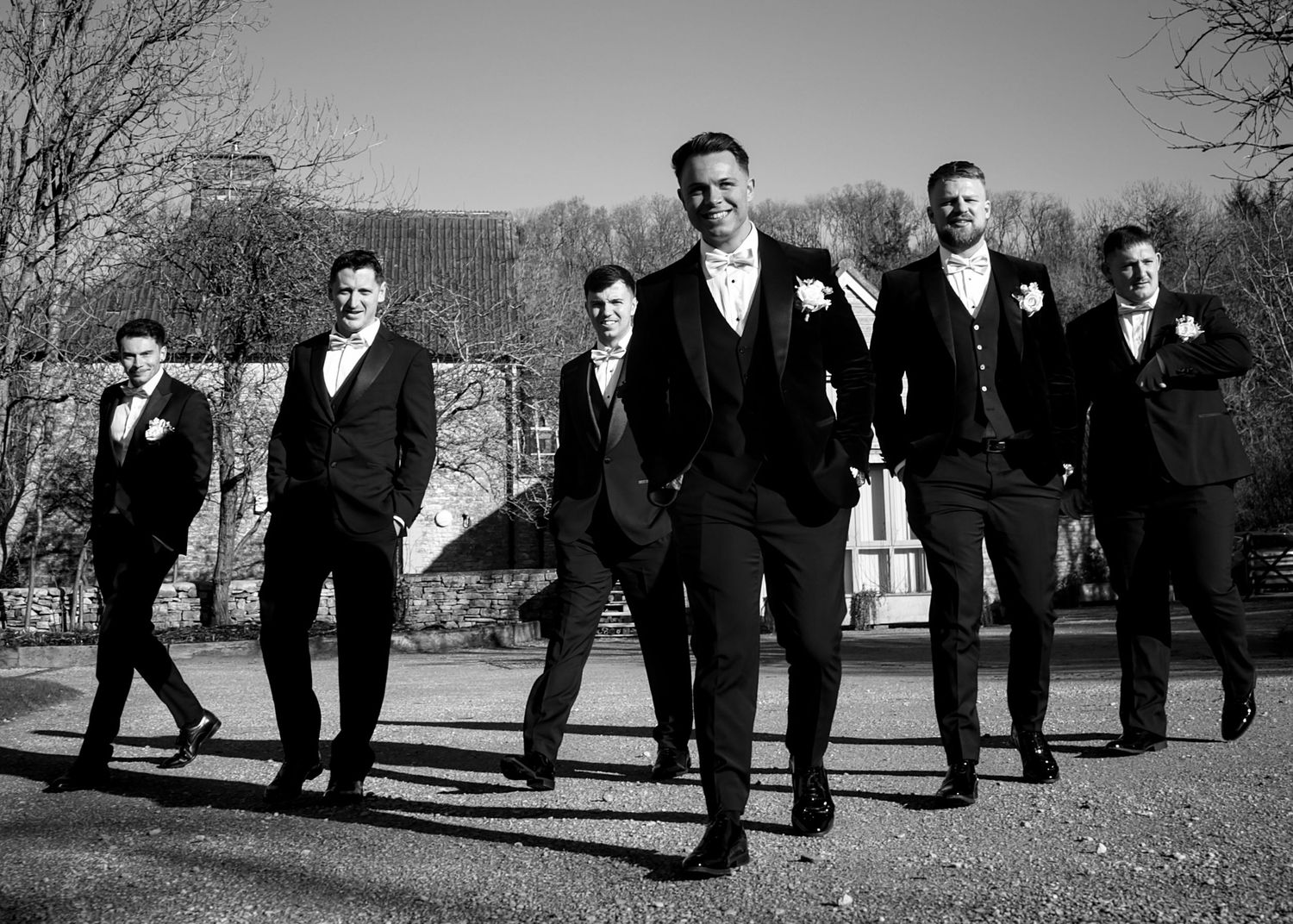 A dramatic black and white photo of groomsmen walking together outdoors.