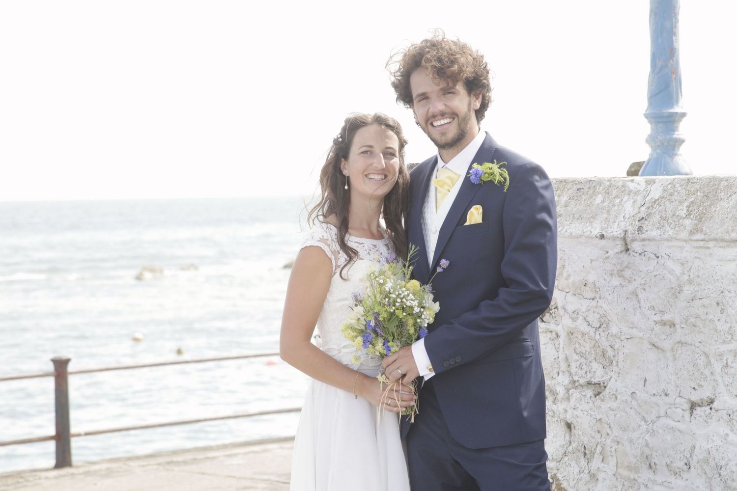 Happy couple shares intimate moment during coastal wedding photoshoot.