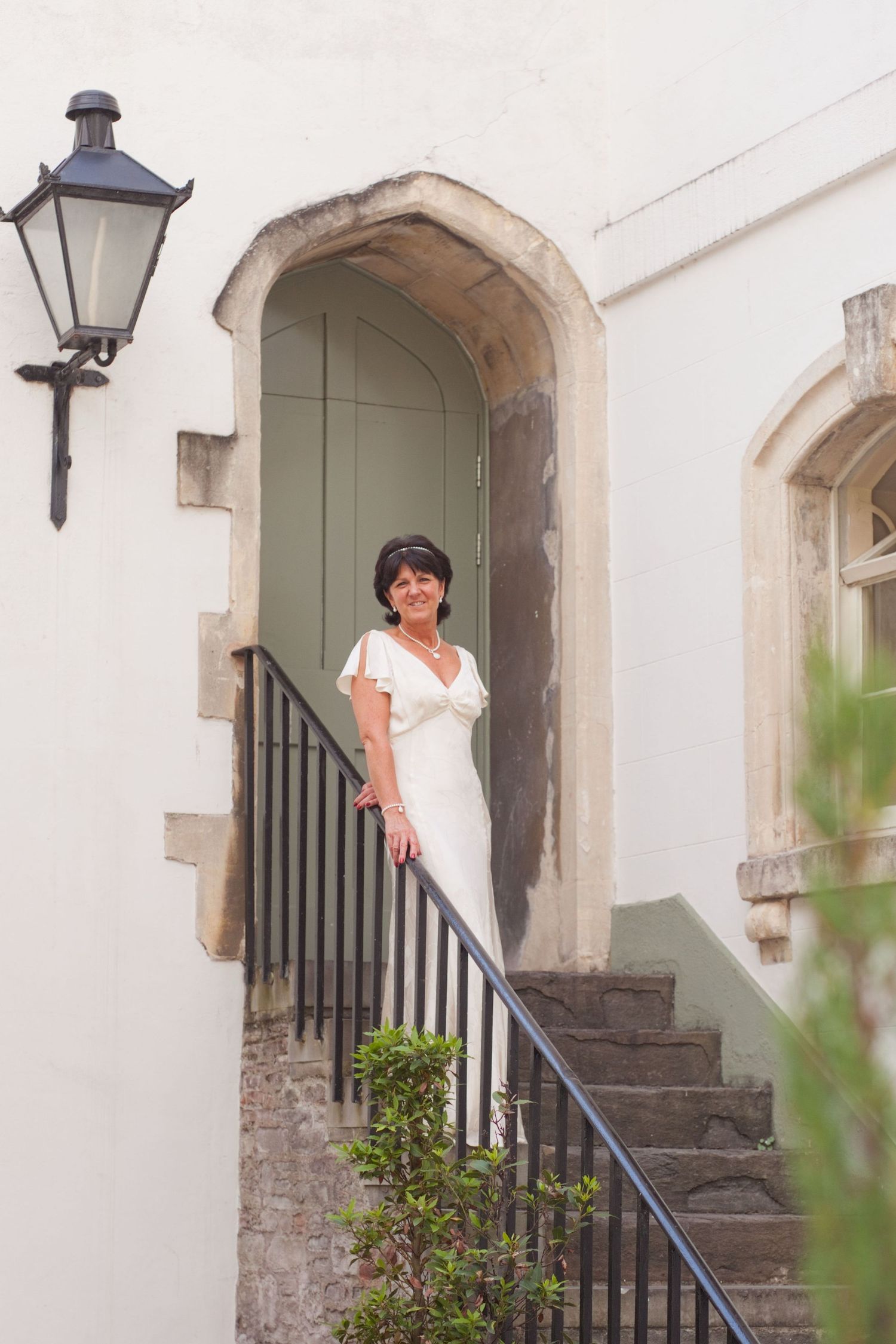 White stone archway entrance with black railings and stone steps leading up.