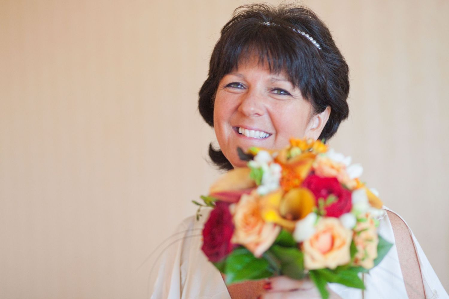 A close-up portrait with a vibrant bouquet of orange, red and pink flowers.