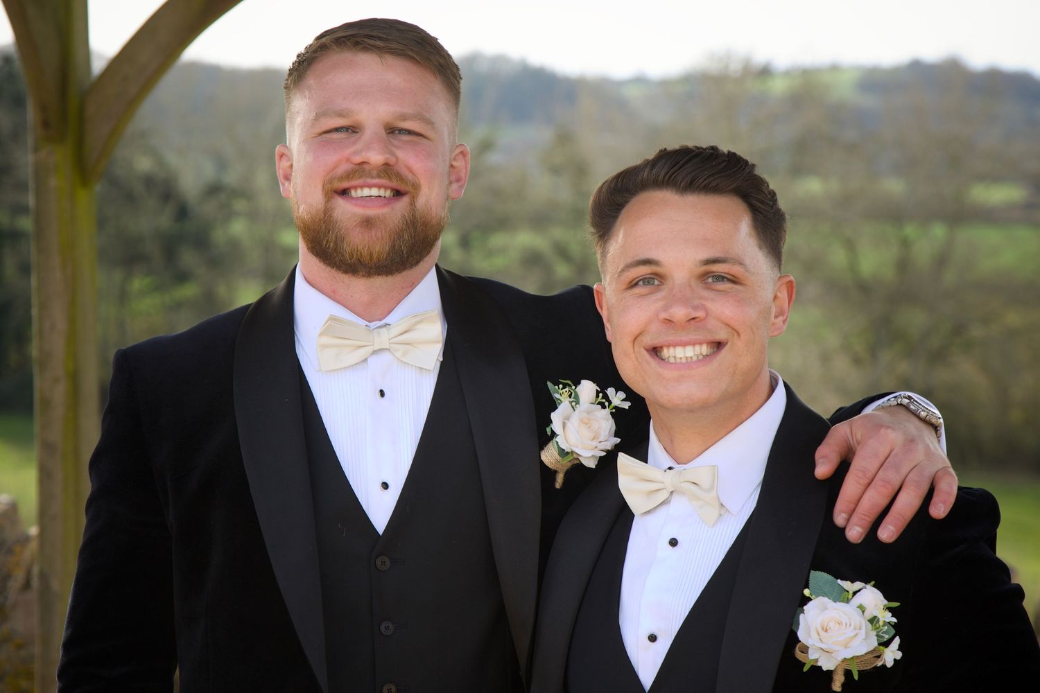 Formal wedding party members in black tuxedos pose together.
