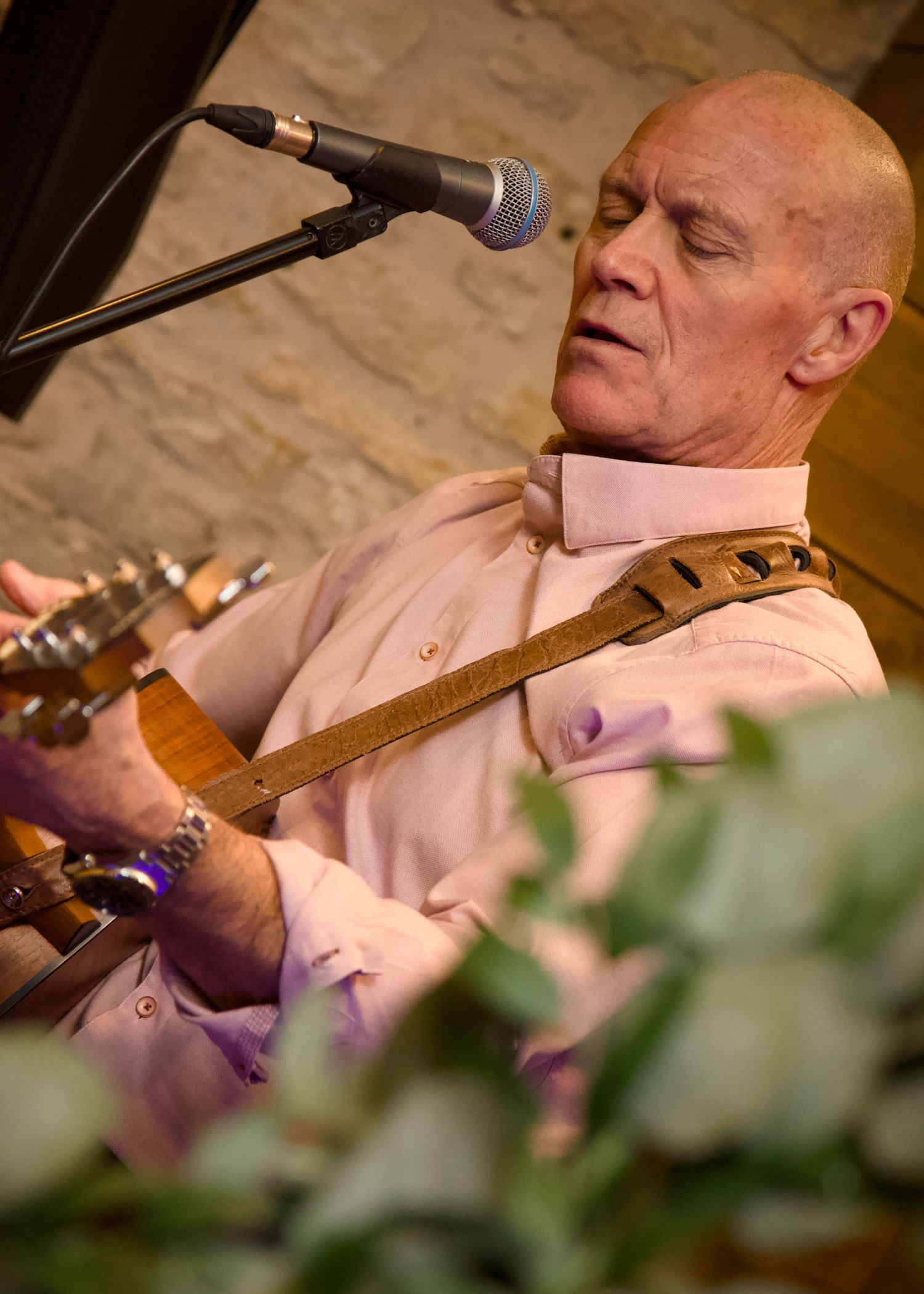 Musician performing with guitar at wedding reception in warm lighting.