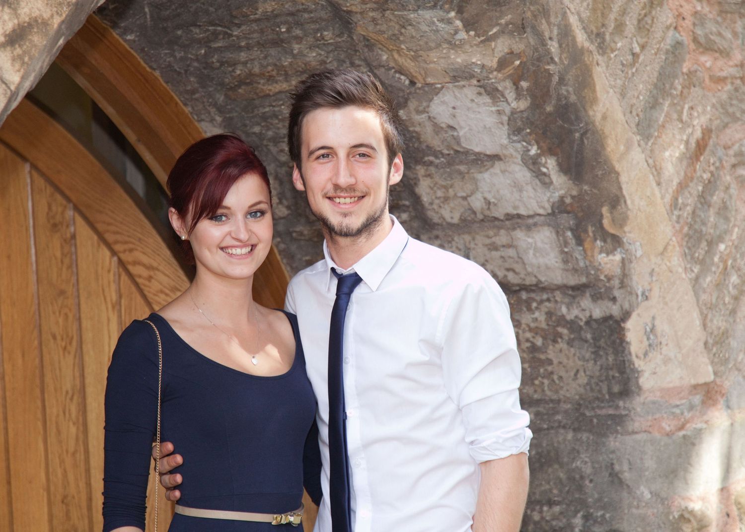 Couples posing together against a stone wall background.
