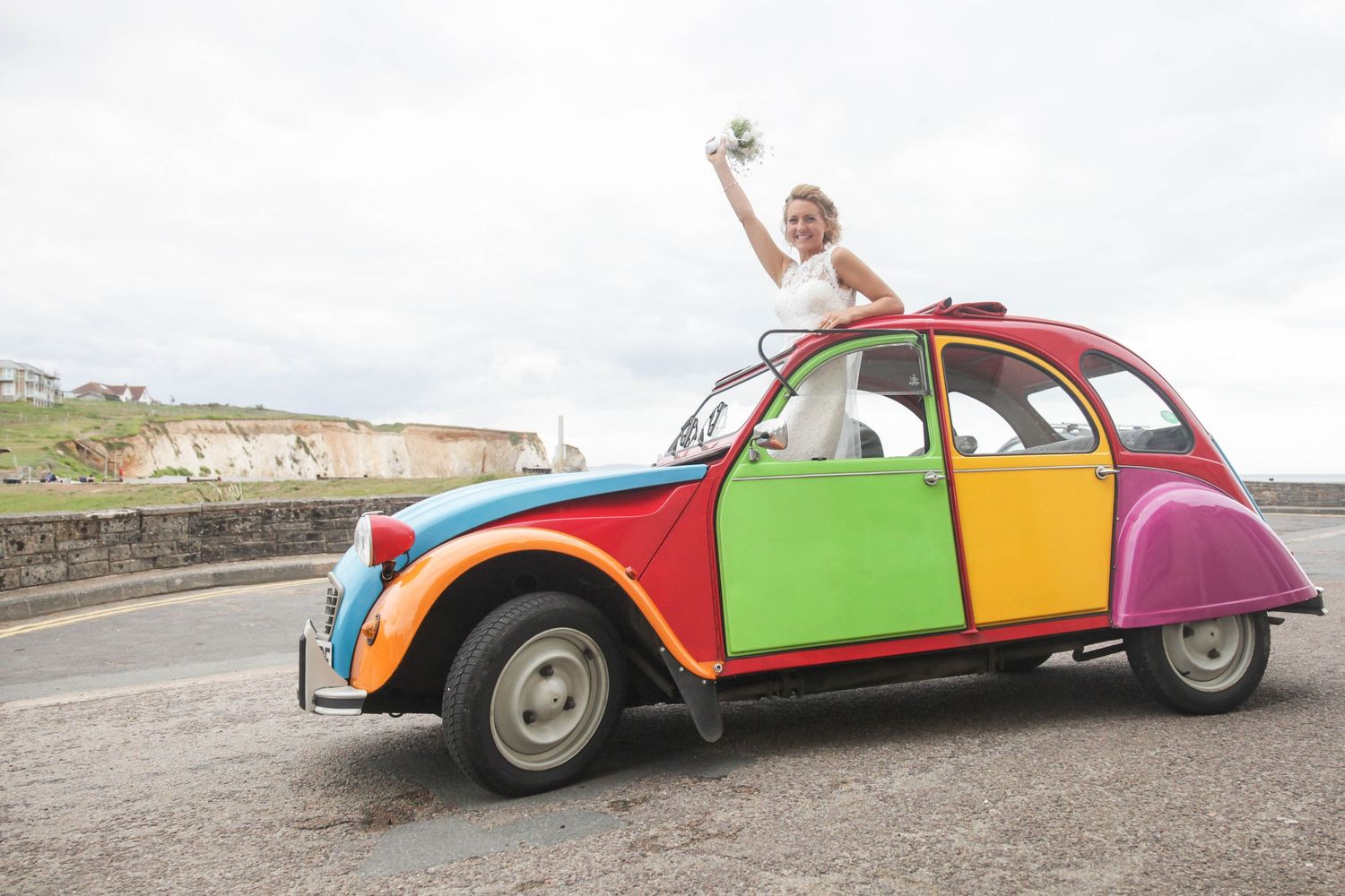 A colorful vintage Citroen 2CV car decorated for a wedding celebration.