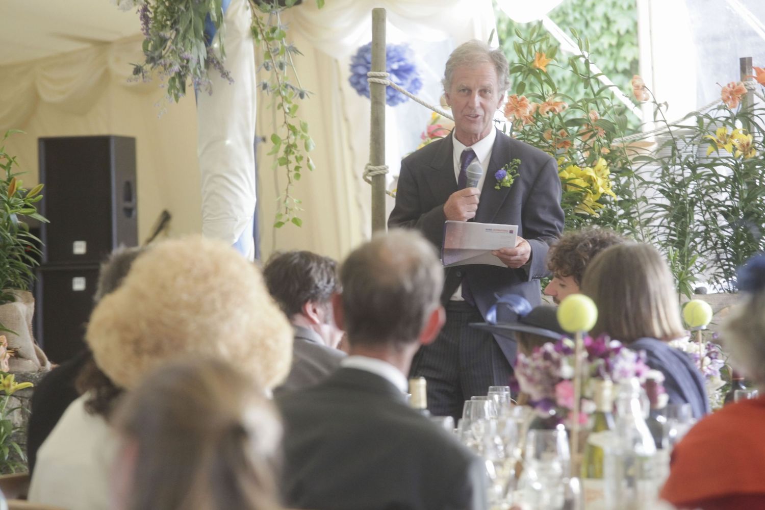 Wedding reception guests mingling under decorative greenery and floral arrangements.